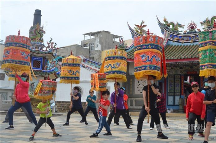 Visitors to Penghu County's Magong experience parasol spinning, a traditional performance art in the region, in this CNA file photo Magong